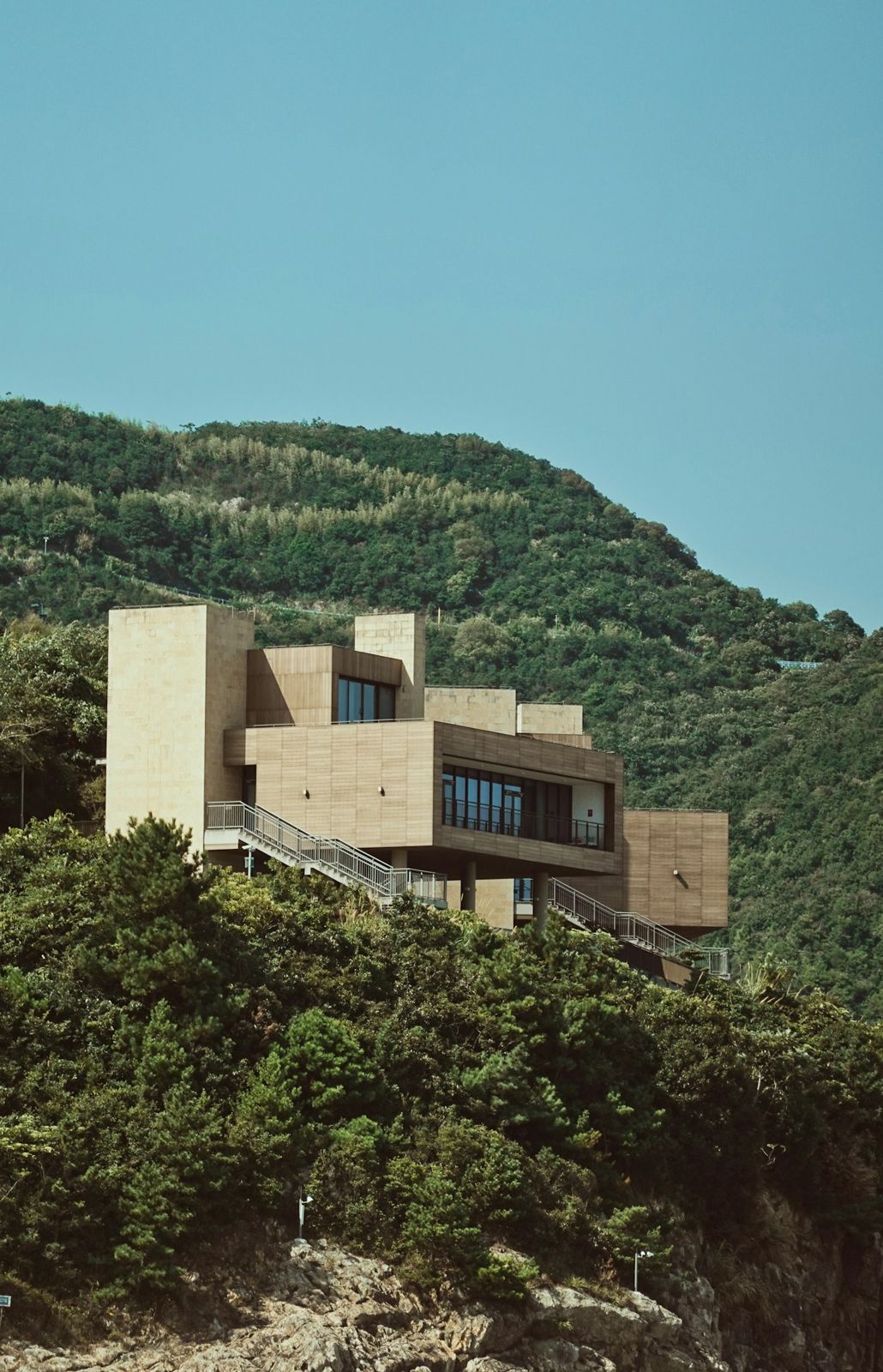 A stone and glass house set into a green hillside
